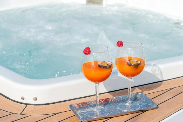 Close-up shot van twee glazen van een cocktail met maracuya in de buurt van de jacuzzi — Stockfoto