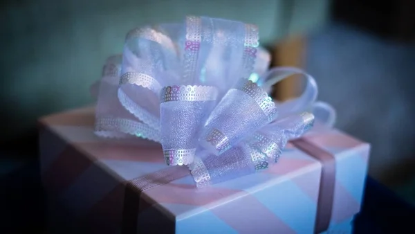Primo piano di una scatola regalo bianca e rosa con nastro adesivo su uno sfondo sfocato — Foto Stock