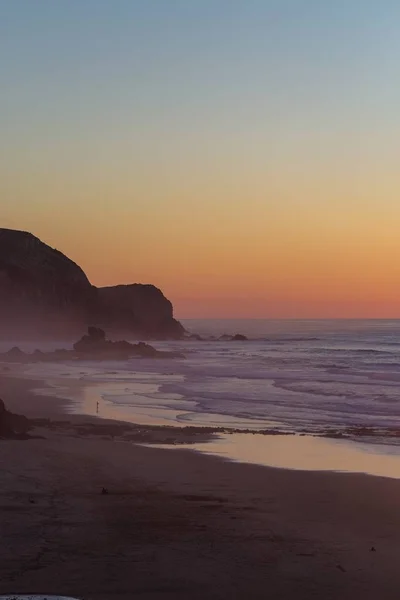 Imagem vertical do mar rodeado de rochas e coberto de nevoeiro durante o pôr-do-sol em Portugal — Fotografia de Stock