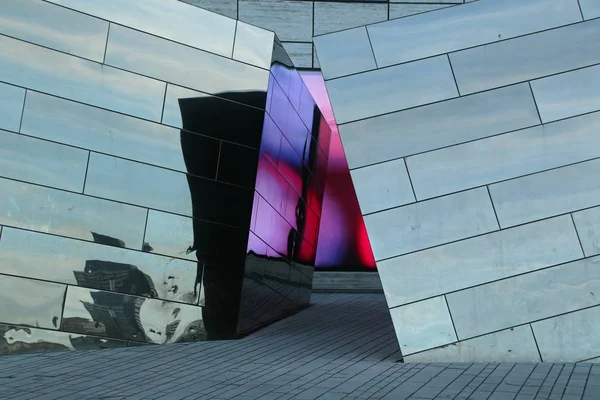 A modern architectural structure in a glass facade with the reflection of color patterns