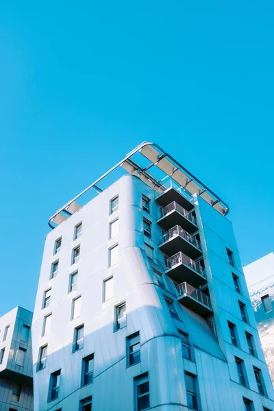 Disparo vertical de ángulo bajo de un edificio geométrico bajo el cielo azul claro — Foto de Stock