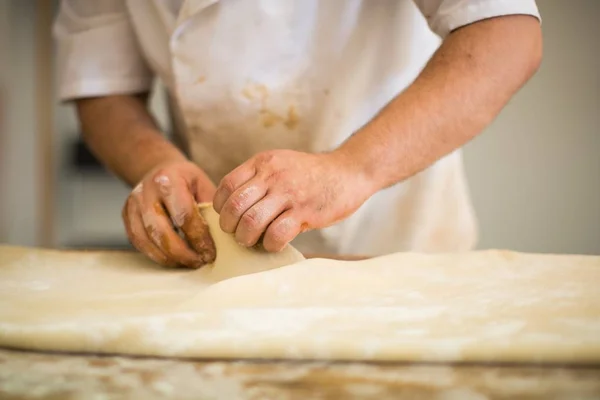 Chefe profissional fazendo uma pastelaria com massa em uma cozinha — Fotografia de Stock