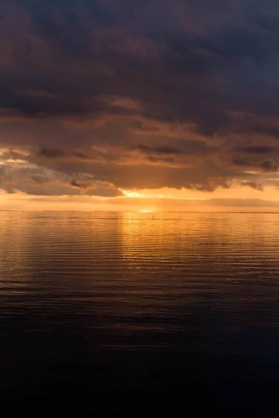 Tiro vertical do pôr do sol de tirar o fôlego no céu nublado sobre o oceano — Fotografia de Stock