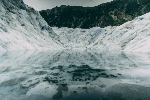 Cenário de tirar o fôlego de um cenário montanhoso meio congelado com neve derretida — Fotografia de Stock