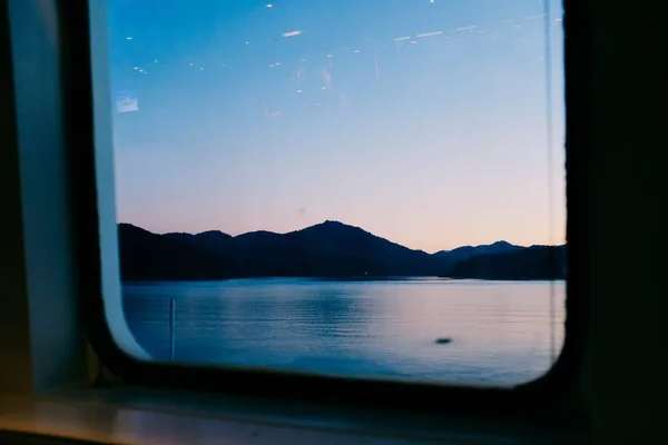 Schöne Aussicht auf den ruhigen Ozean und die Hügel aus einem Fenster eingefangen — Stockfoto
