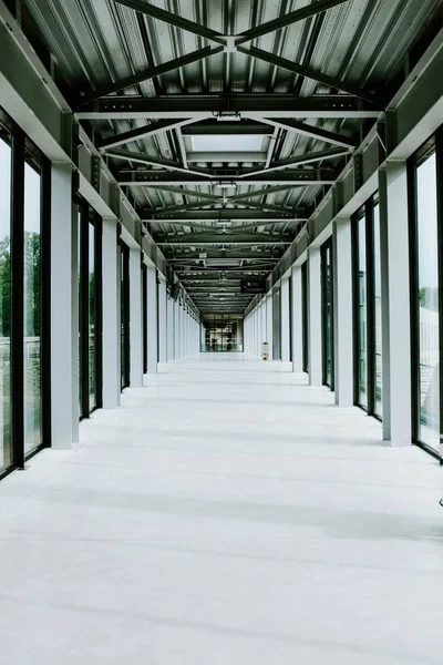 Imagen vertical de un pasillo blanco con puertas de cristal y techo de metal en un edificio moderno — Foto de Stock