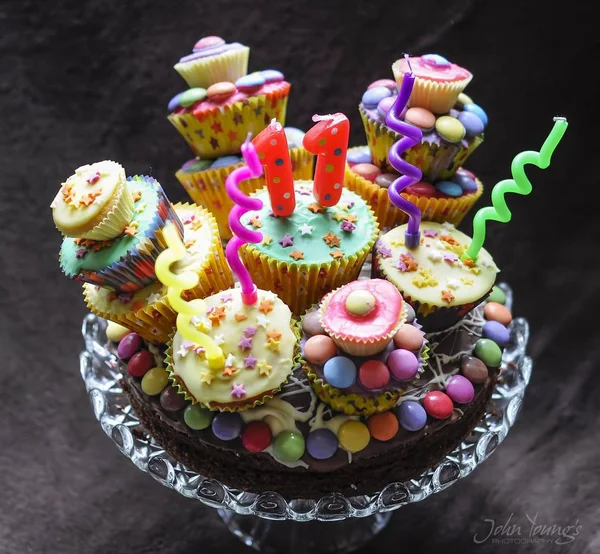 Tiro de alto ângulo de um delicioso bolo de chocolate com decoração de cupcakes coloridos — Fotografia de Stock