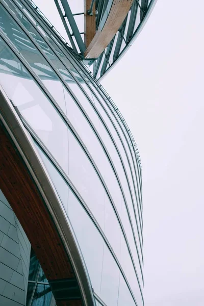 Κοντινό πλάνο ματιά ενός σύγχρονου κτιρίου με λευκά γυάλινα παράθυρα κάτω από ένα γκρίζο ουρανό — Φωτογραφία Αρχείου