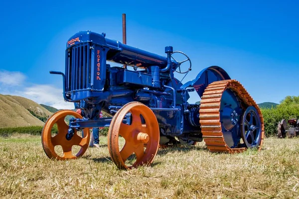Camion agricolo blu con ruote arancioni su un campo erboso a Otaki in Nuova Zelanda — Foto Stock
