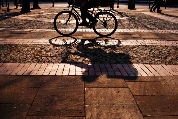 一个骑自行车的人的影子伸展在美丽的铺面街道上 — 图库照片
