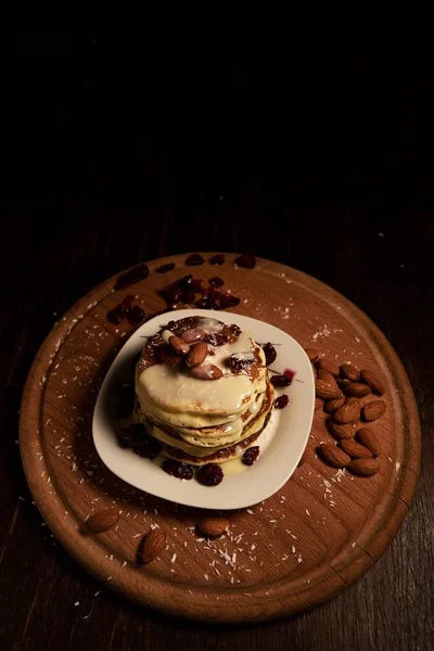 En bunt pannkakor med vit sirap och mandel ovanpå en trälåda täckt med bakpulver — Stockfoto