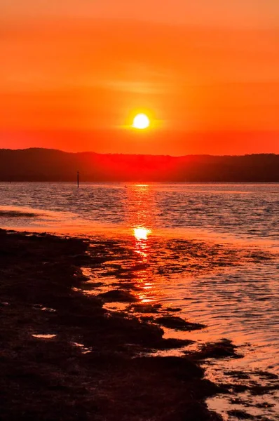 Vertical shot of the beautiful sunset in the colorful sky over the calm ocean — Stock Photo, Image