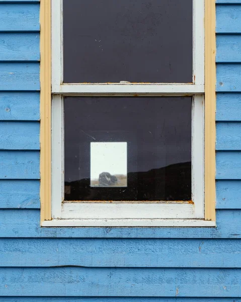 Tiro vertical de uma janela em uma parede azul de madeira de uma casa de campo — Fotografia de Stock