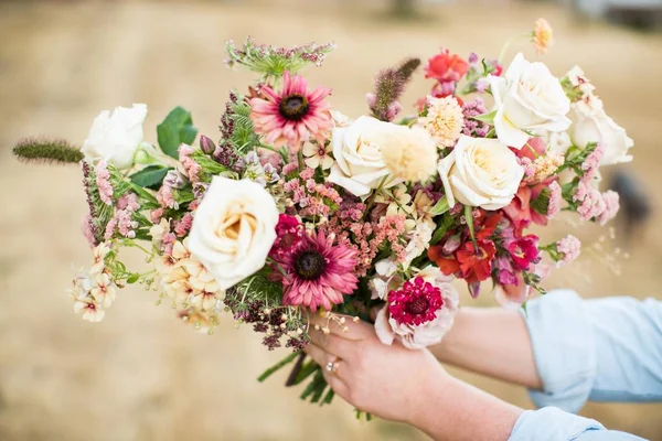 A person holding a beautiful flower bouquet with a blurred background