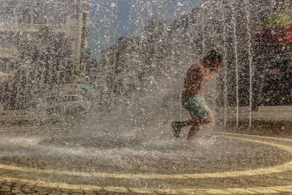 Человек, бегущий через водные фонтаны в парке — стоковое фото