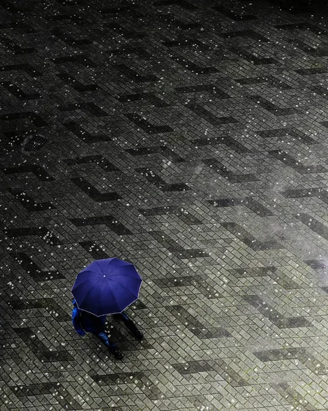 Imagen vertical en escala de grises de una persona que camina en un día lluvioso con colores azules visibles —  Fotos de Stock