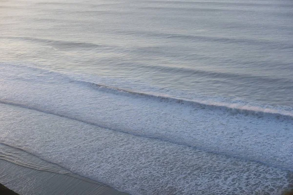 Primer plano de olas del océano en calma moviéndose hacia la orilla durante el tiempo de la noche —  Fotos de Stock