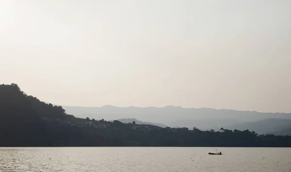 大海的风景，岛上有一条船，四周环绕着群山，天空灰蒙蒙，绿油油的 — 图库照片