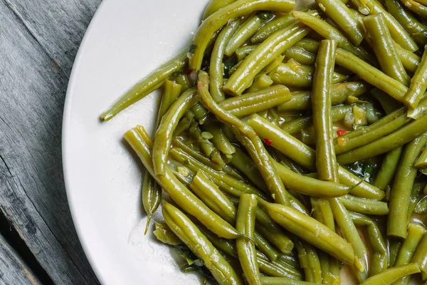 Tiro de alto ângulo de feijão verde cozido em uma placa branca - perfeito para um artigo sobre comida vegana — Fotografia de Stock