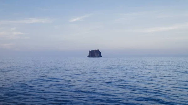 Paesaggio del mare con una roccia sullo sfondo sotto un cielo nuvoloso durante il giorno — Foto Stock
