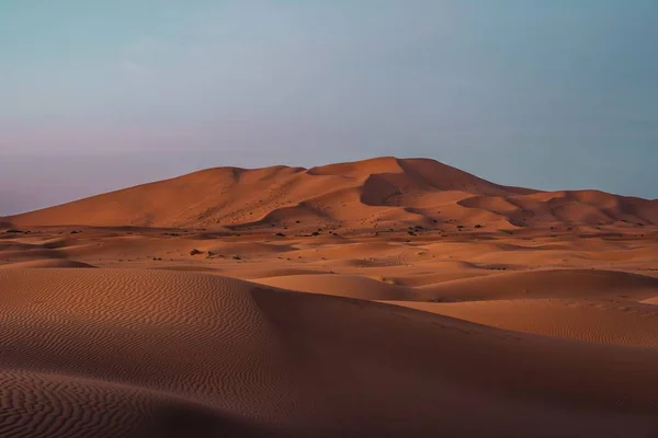 Landschap van een woestijn omringd door heuvels onder een blauwe hemel tijdens de avond — Stockfoto