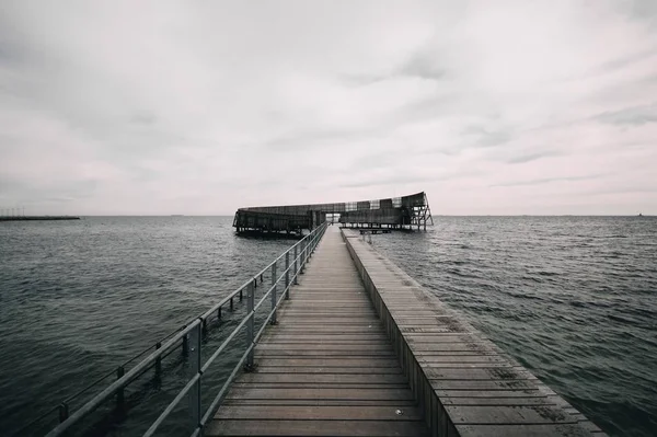 Pier levando ao oceano calmo sob o céu sombrio — Fotografia de Stock