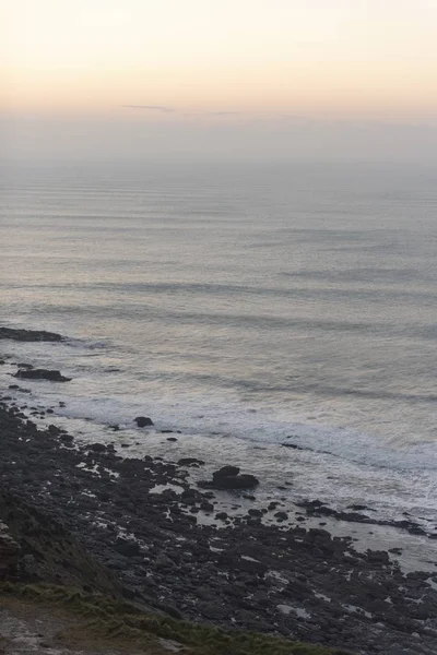 Colpo verticale di onde oceaniche calme che si muovono verso la riva durante l'ora serale — Foto Stock