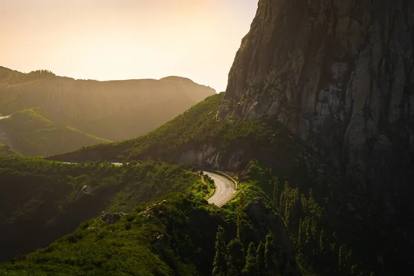 Пейзаж гор, покрытых зеленью с дорогами на них под облачным небом на закате — стоковое фото
