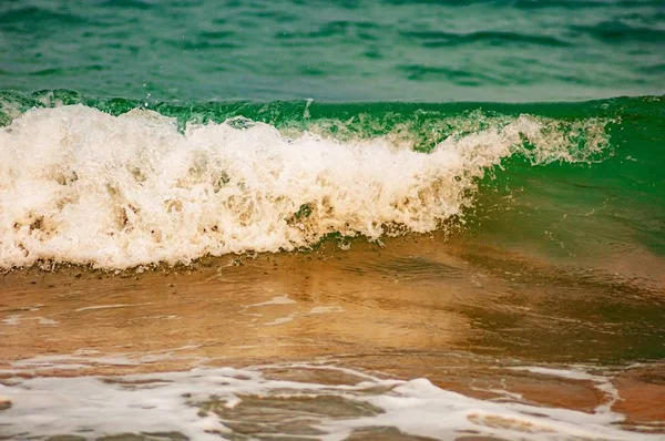 在沙滩上浸透的绿松石海浪中的特写镜头 — 图库照片