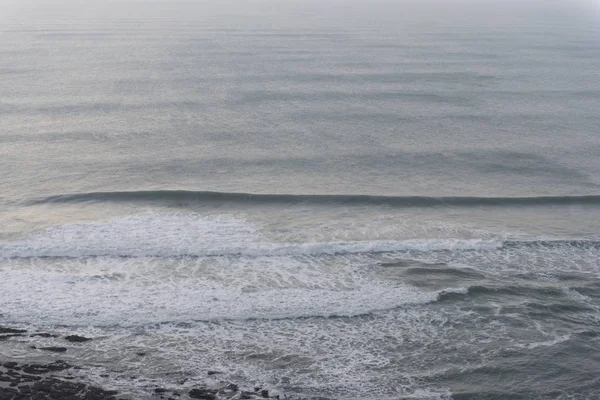 Primer plano de olas del océano en calma moviéndose hacia la orilla durante el tiempo de la noche — Foto de Stock