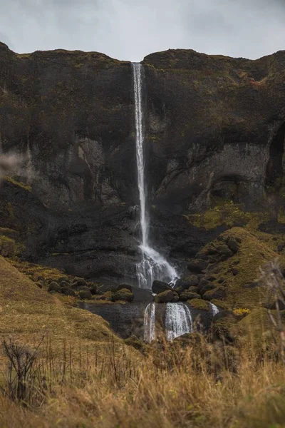 Uma Cachoeira Cercada Por Rochas Grama Seca Sob Céu Nublado — Fotografia de Stock