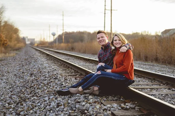 Happy white couple sitting on the railways enjoying each other's company — ストック写真