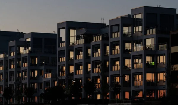 A concrete apartment building with reflective windows during sunset