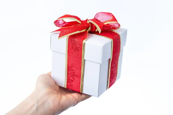 一只手拿着一个白色礼品盒 用红色的带子包裹在白色的背景上 — 图库照片
