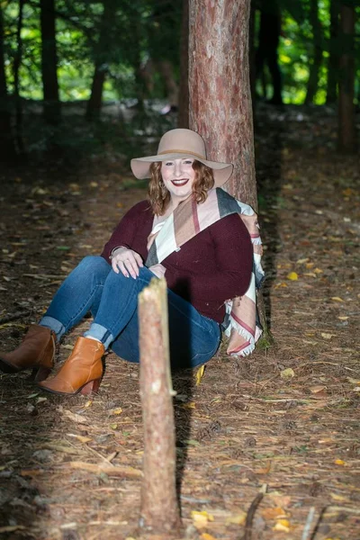 Smiling Woman Red Blouse Hat Sitting Ground Leaning Tree Forest — стоковое фото