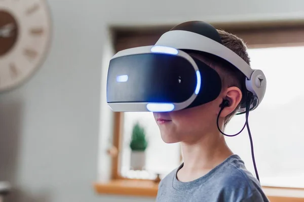 Tembakan jarak dekat seorang anak laki-laki berdiri serius di dalam ruangan sambil mengenakan headset virtual reality — Stok Foto