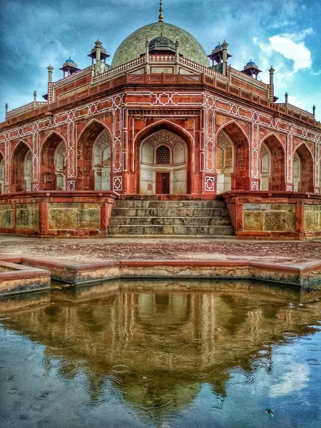 The tomb of the Mughal Emperor Humayun reflecting on the rain under a cloudy sky in Delhi in India