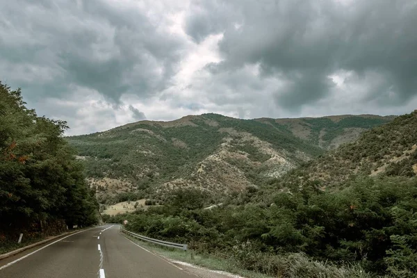 Uma Estrada Meio Uma Paisagem Montanhosa Sob Céu Sombrio — Fotografia de Stock