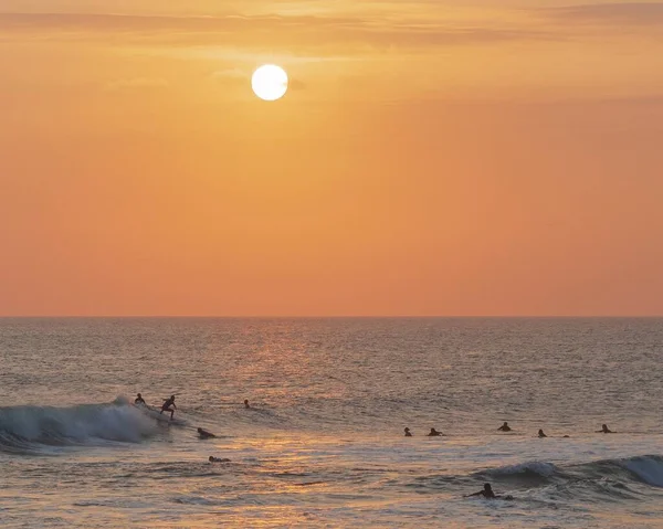Пейзаж моря з людьми, які плавають в ньому під час прекрасного заходу сонця — стокове фото