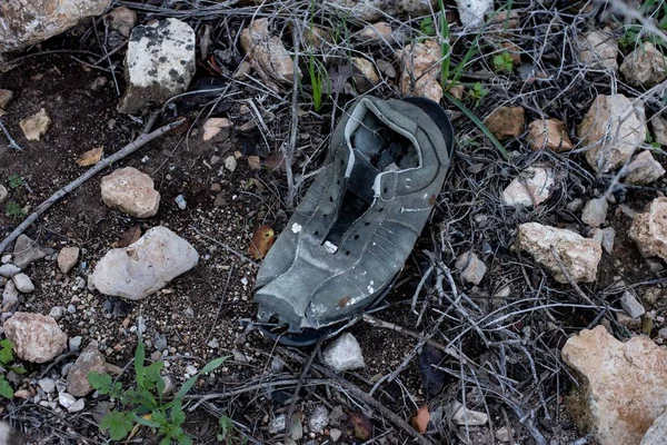 岩や小石で覆われた道に取り残された古い靴の高い角度のショット — ストック写真