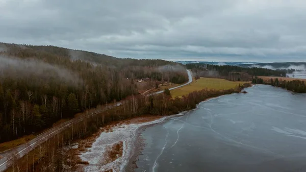 スウェーデンの真ん中に凍った湖があるフィールドに囲まれた道路の高角度のショット — ストック写真