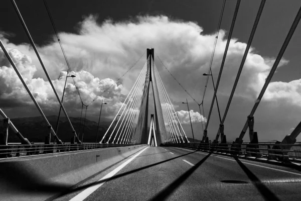 Uma Escala Cinza Uma Ponte Cabo Permanecido Com Montanhas Fundo — Fotografia de Stock
