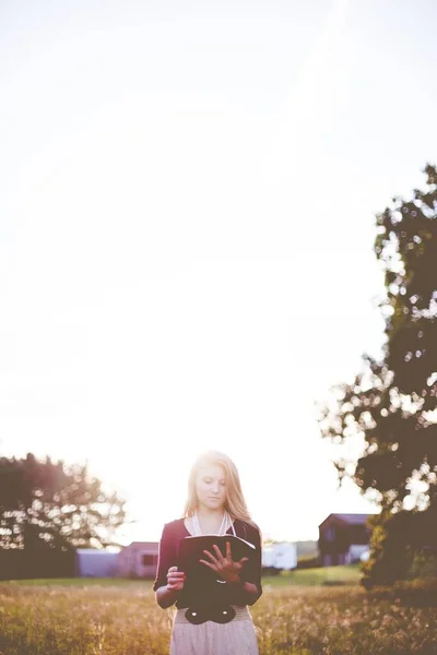 Shallow focus shot of a white female reading the Bible under the bright rays of the sun — Fotografia de Stock