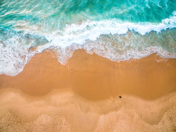 一个孤独的人在美丽的海浪附近的海滩上散步的高角镜头 — 图库照片