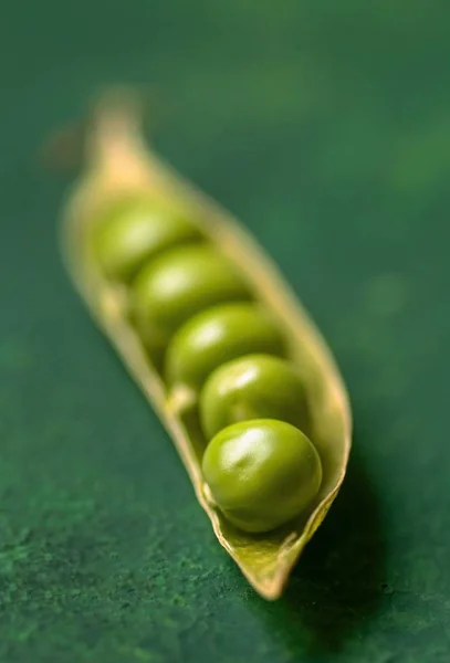 緑のぼやけた背景を持つスナップエンドウ豆の豆の垂直選択的焦点ショット — ストック写真