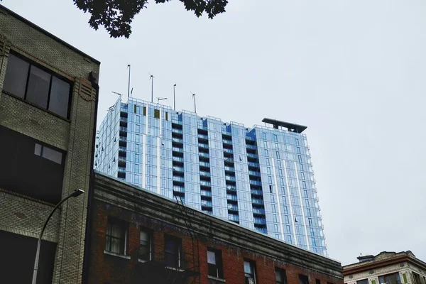 Low Angle Shot Modern Building Surrounded Older Buildings Clear Sky — Stock Photo, Image