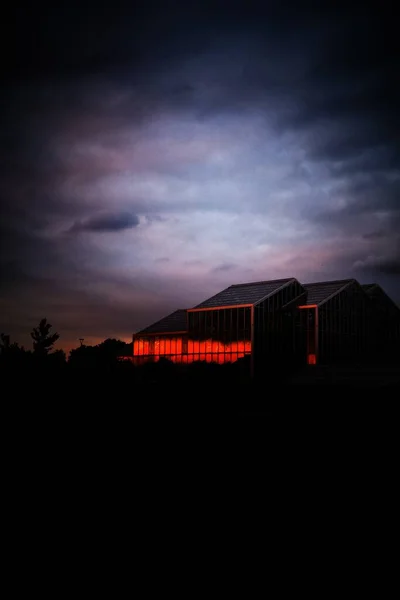 Egy Függőleges Felvétel Egy Épületről Egy Üveghomlokzaton Viharfelhők Alatt Éjszaka — Stock Fotó