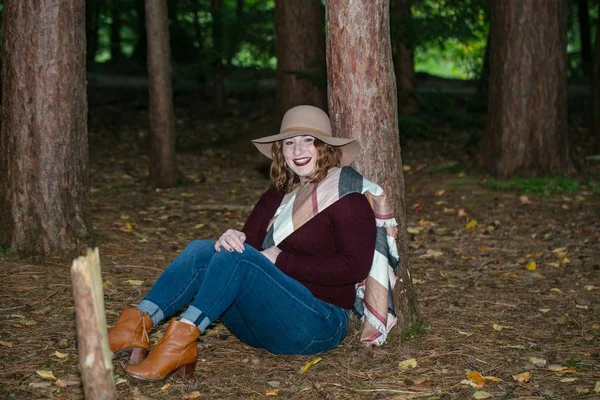 Smiling Woman Red Blouse Hat Sitting Ground Leaning Tree Forest — стоковое фото