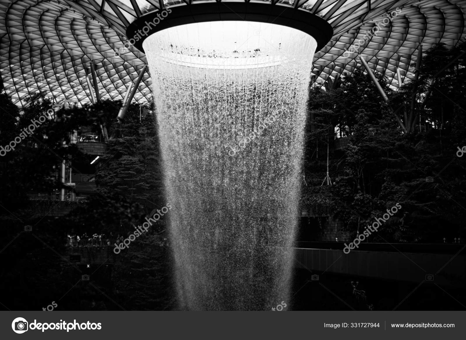 Greyscale of a Changi airport fountain surrounded by greenery during ...