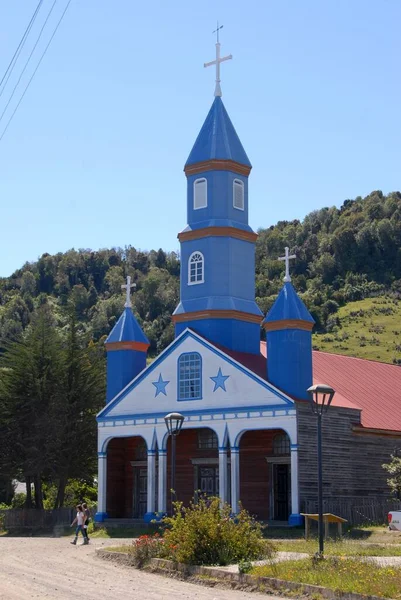 Verticaal beeld van een kerk met bomen en blauwe lucht op de achtergrond — Stockfoto